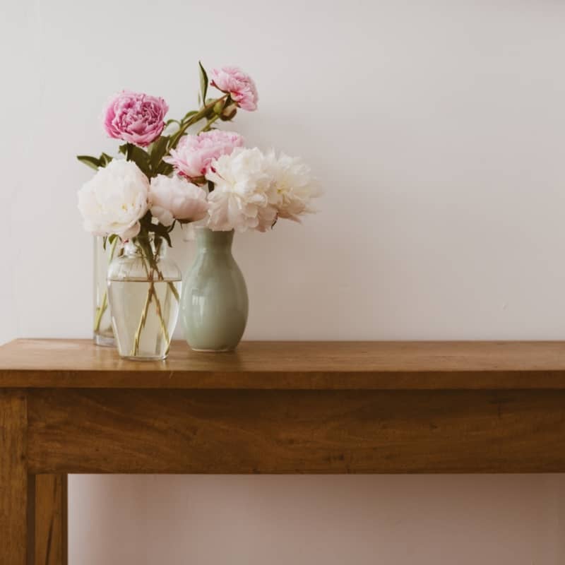Pink - Pink and white peonies in glass and ceramic vases on oak wooden table against neutral wall -