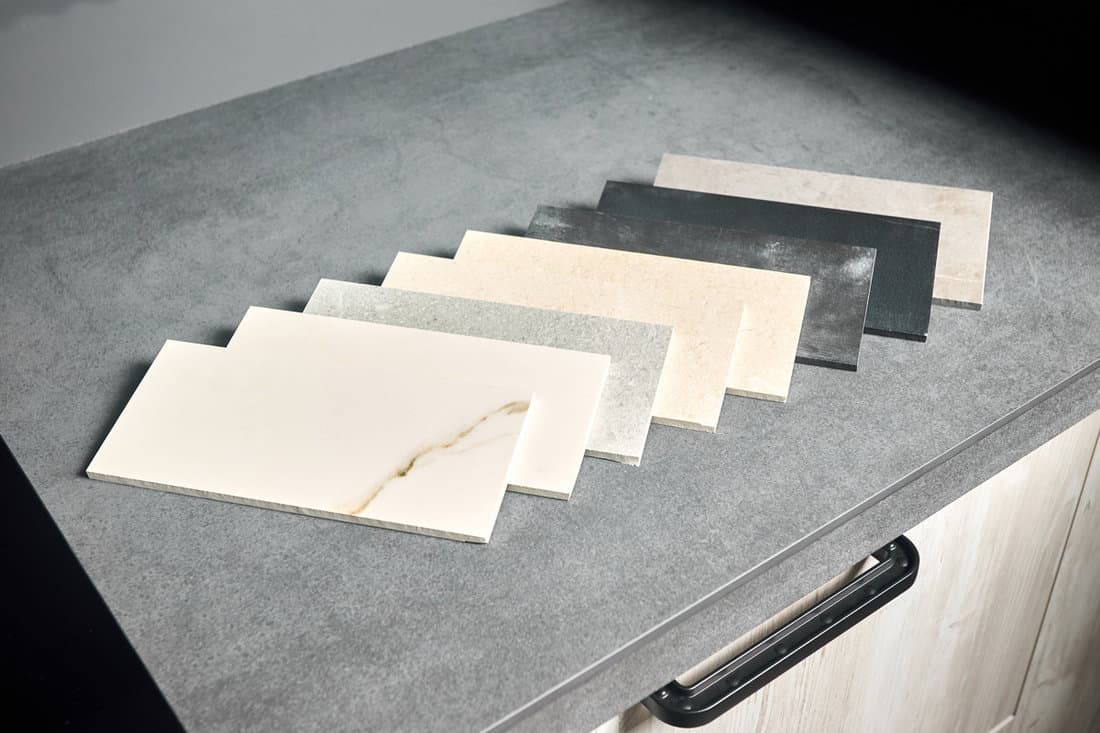 Porcelain stoneware square samples laid on kitchen countertop as examples of future kitchen fasade exterior.
