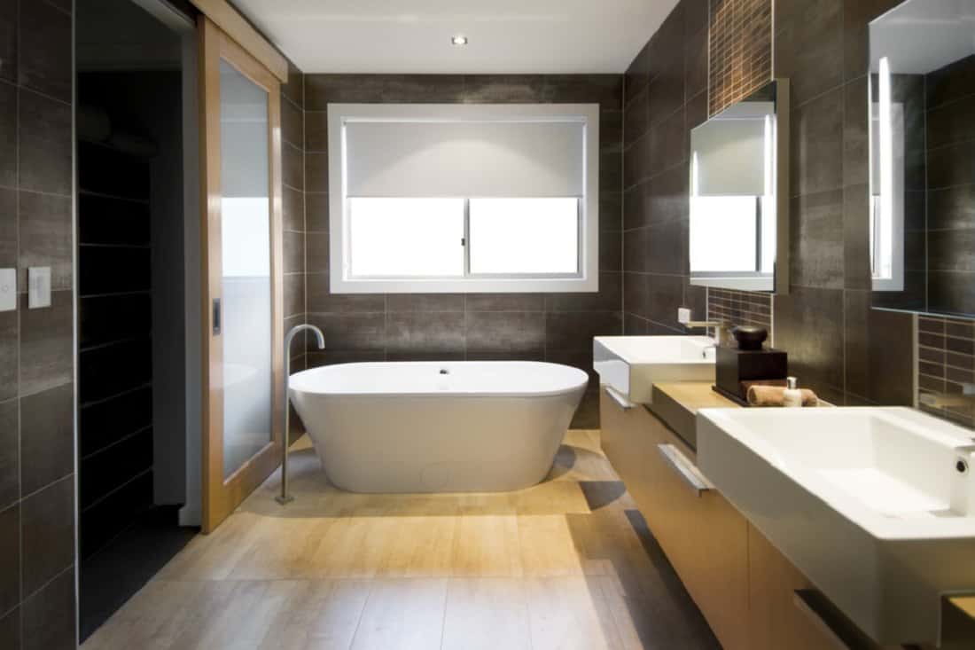 Rigid Core Engineered Wood - Australian Luxury bathroom with brown tiles and hardwood floor, focusing on a free standing bath.