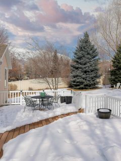 Snow covered deck of a house with white railing and wood planks, Why Is My Deck Popping In The Cold?