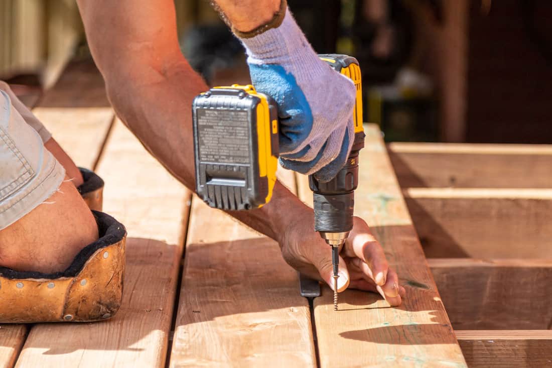Strong hands preparing wooden boards in construction work outside in bright sunlight
