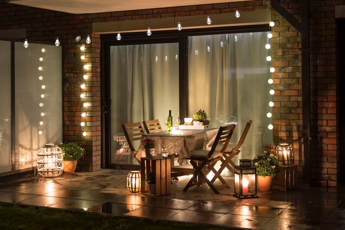 Summer evenig terrace with candles, wine and lights on the wall attached