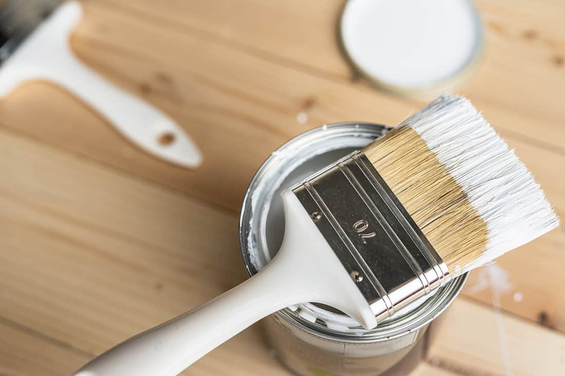 Top view on white paint brush on the opened can on the wooden table