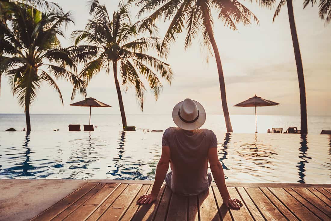 Tourist in luxury beach hotel near luxurious swimming pool at sunset