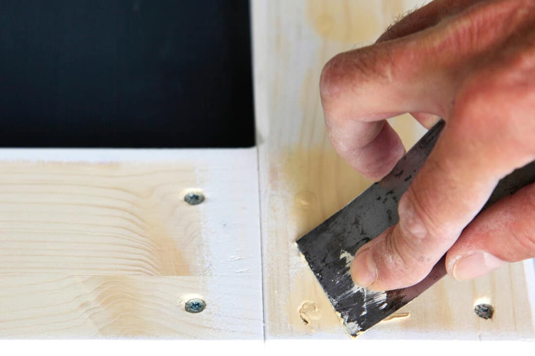 Using a putty knife in applying wood filler nail holes