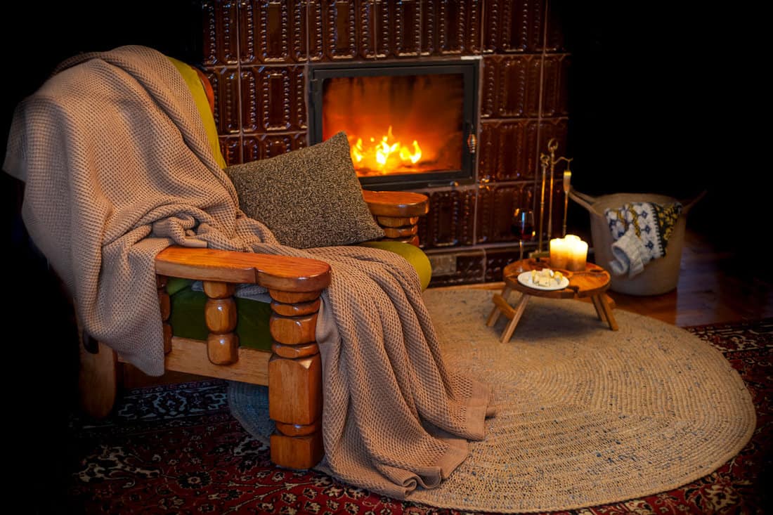 Vintage wooden armchair with knit blanket in cozy cabin room outside the city with fireplace