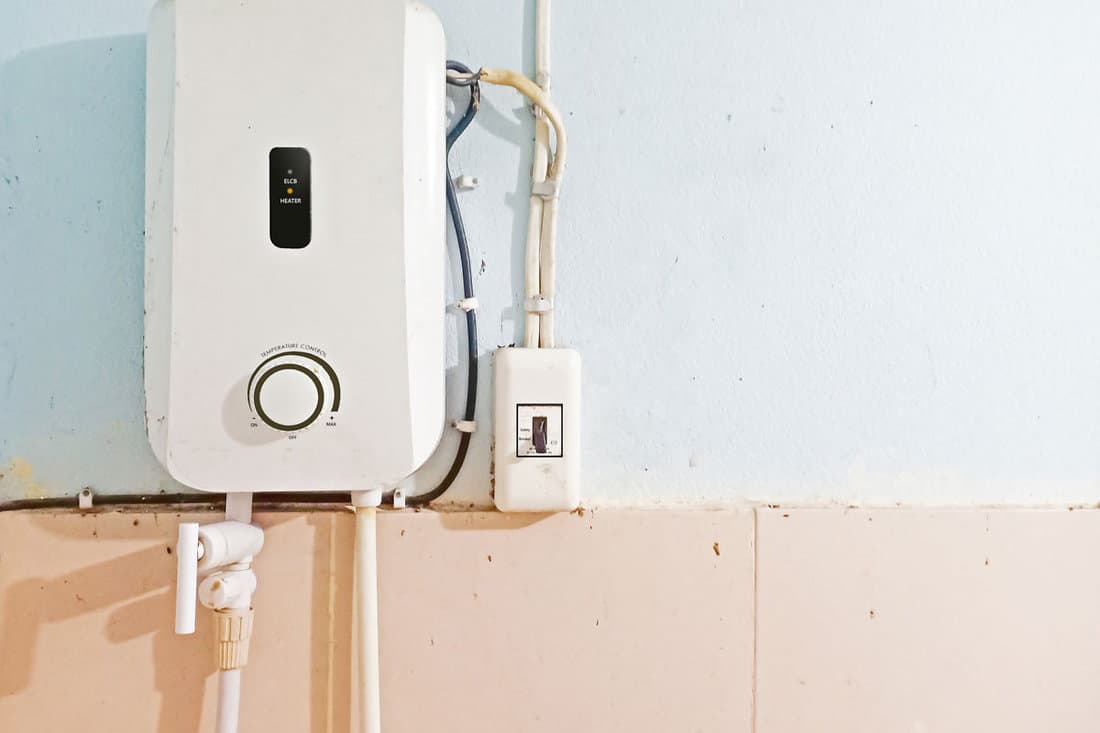 White instant water heater installed with circuit breaker on the wall of bathroom