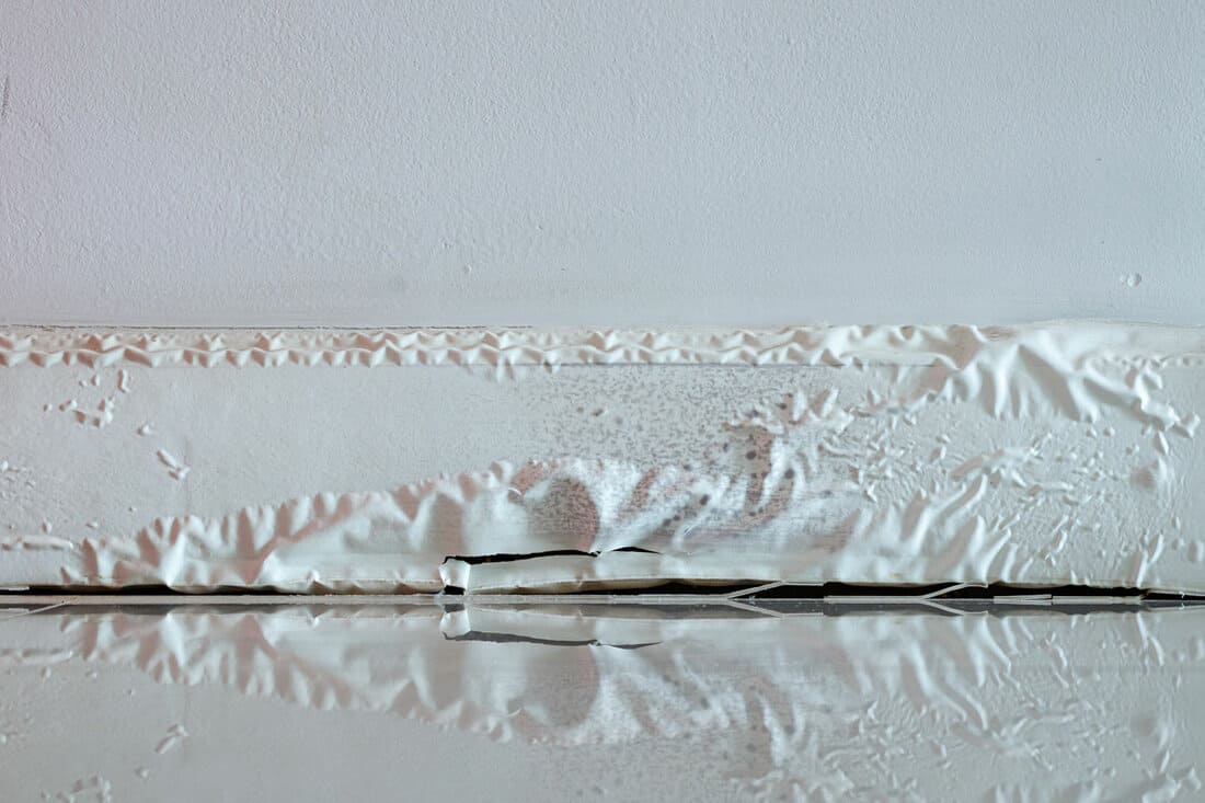 White skirting board damaged by destructive elements from moisture or water