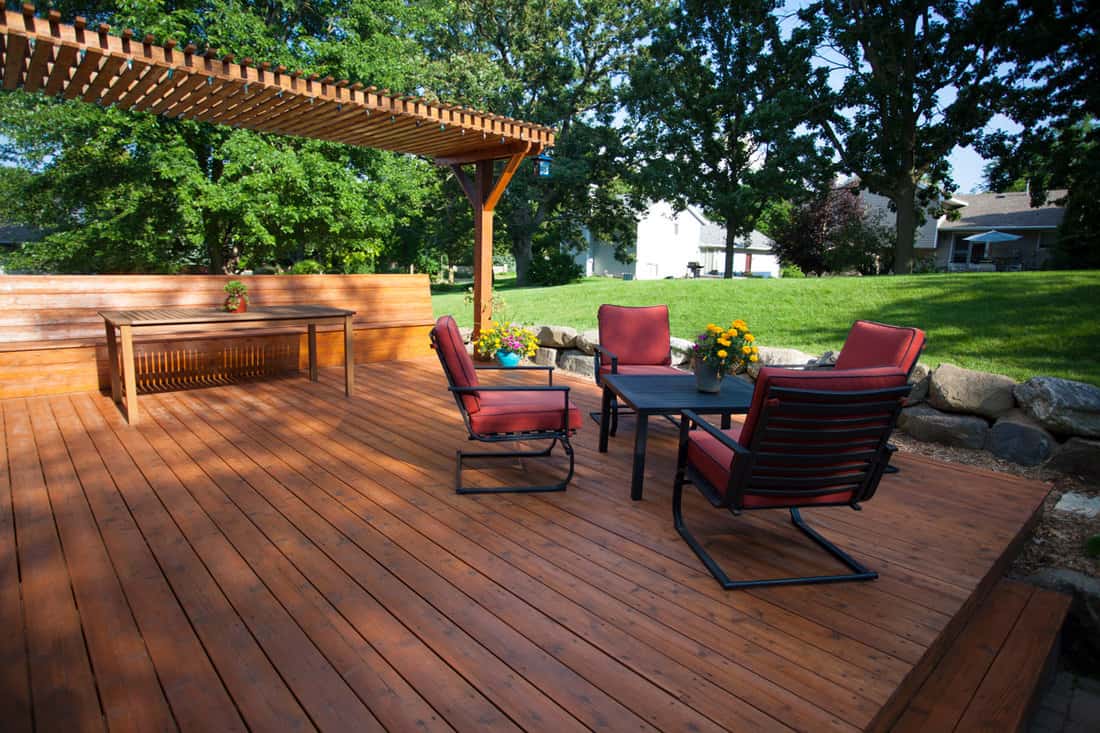 Wooden entertainment deck with brown foam chairs anda small trellis on the side