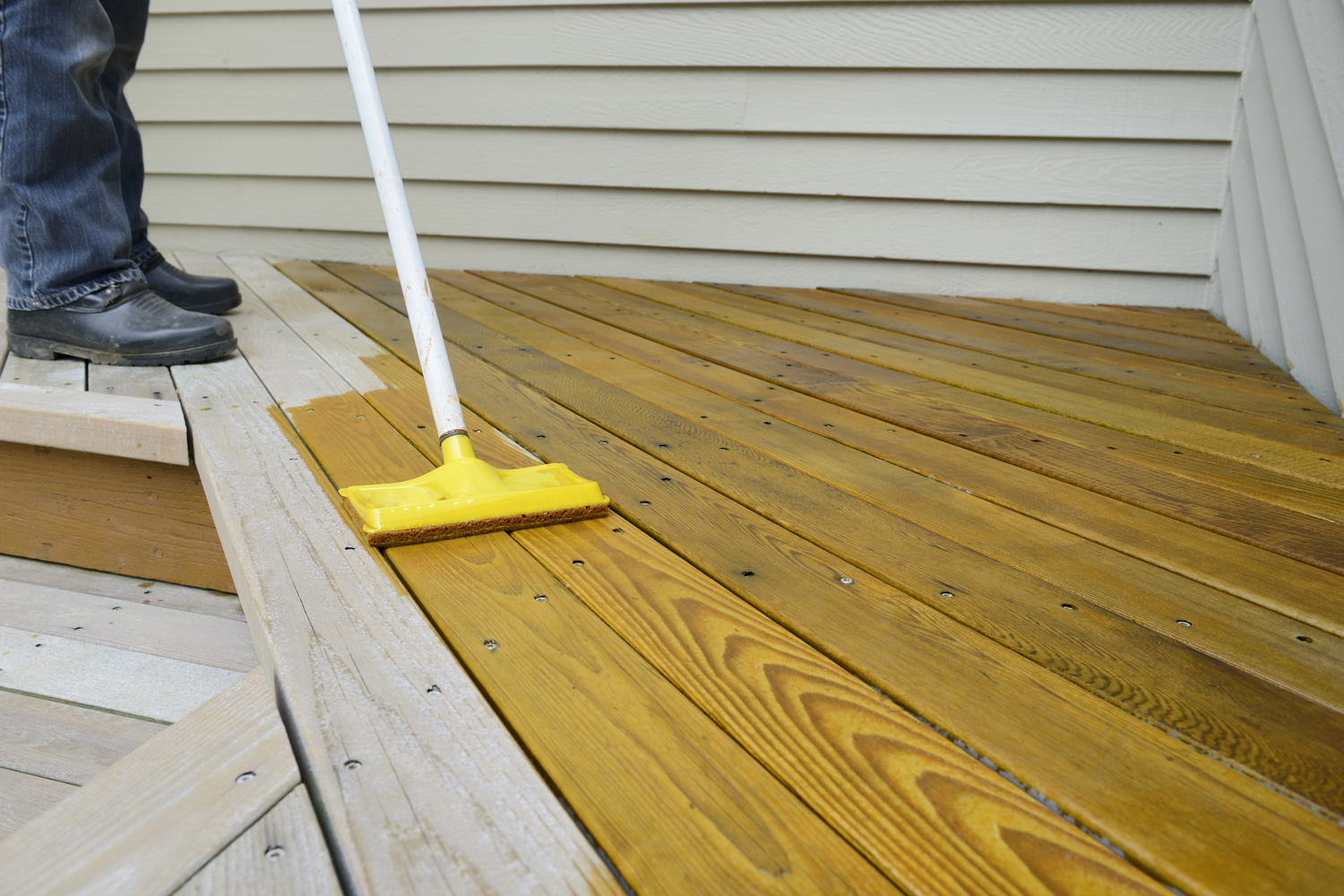 Worker Applying Stain to Deck