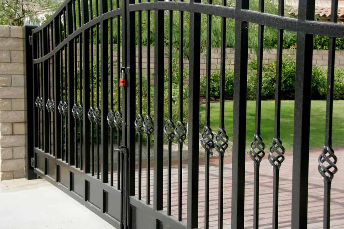 close up photo of a huge black metal gate on the outside of the mansion