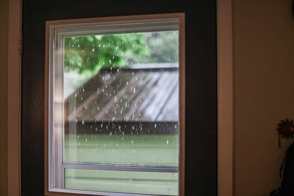 close up photo of a storm door captured inside the house during the rainy day