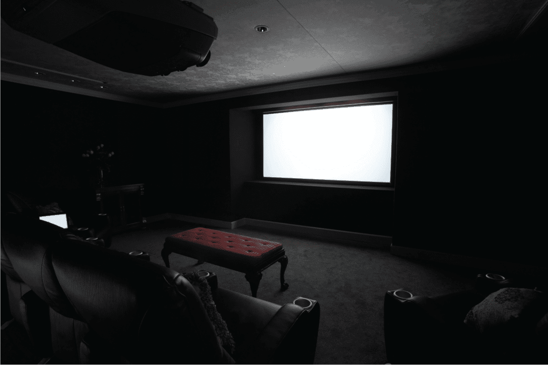 dark home theater room with lit projector screen