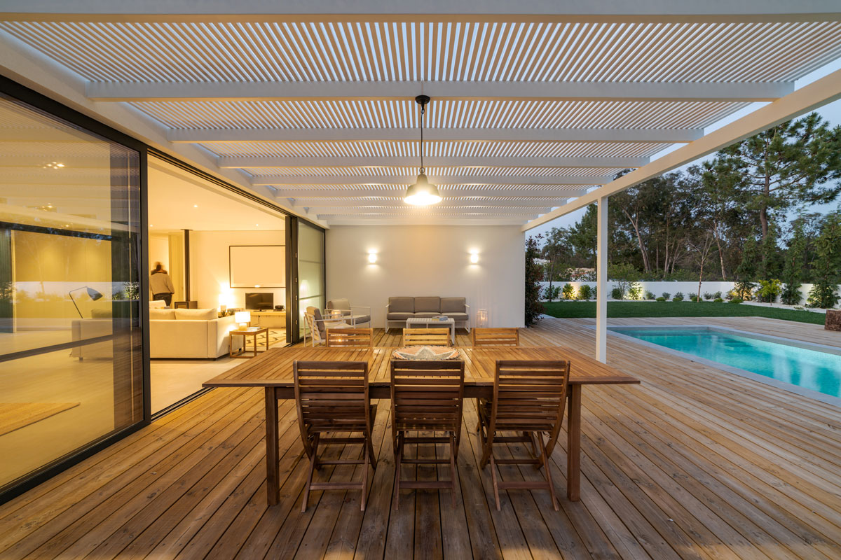 good looking outdoor dining table by the pool side, wood deck floor, warm lights