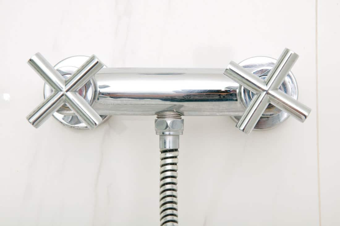 photo of a shower stainless steel faucet inside a marble tiled bathroom 