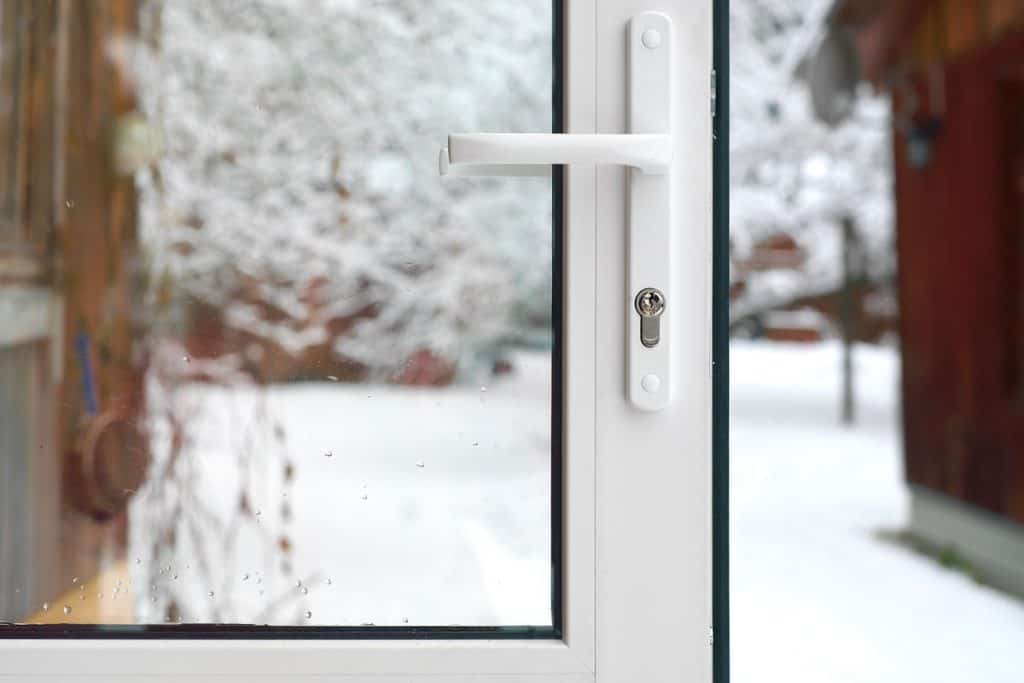 photo of a storm door opened on outside of the house on a snowy day