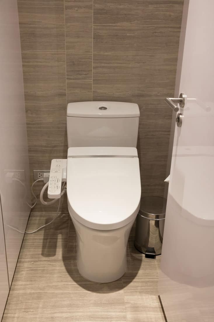 portrait photo of a toilet on a bathroom, brown wall tile, modern bathroom