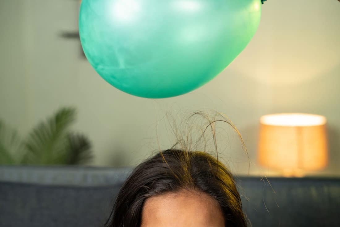 shot of kids playing by placing balloon to attracting hair