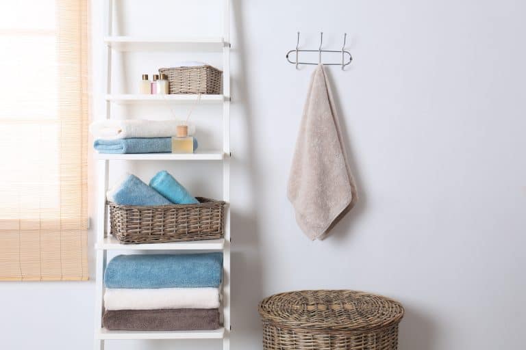 Shelving unit and rack with clean towels and toiletries near white wall - Where To Put Wet Washcloths [5 Actionable Suggestions]