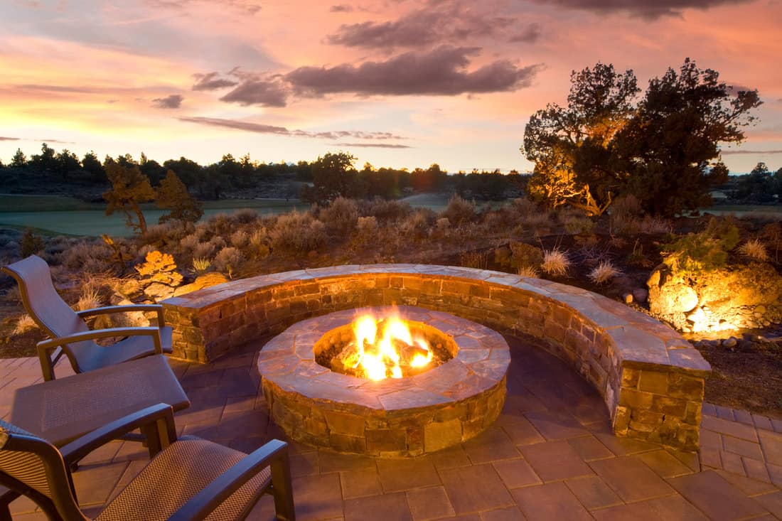 stone fire pit with outdoor chairs, enjoying the sunset and landscape.