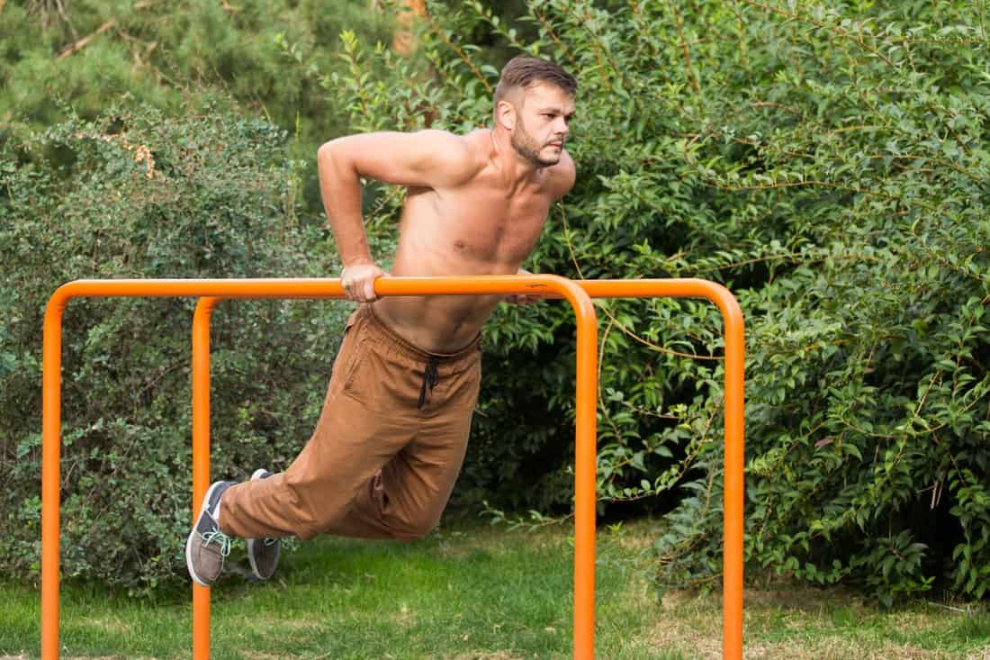 young man doing triceps dip on parallel bars outdoors, How Deep Should Dip Bars Be In The Ground