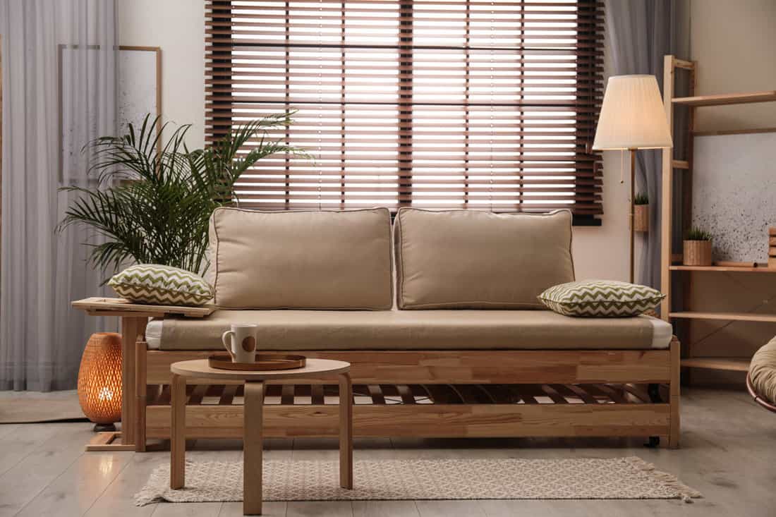 A gorgeous wooden sofa with brown throw pillows and a wooden coffee table