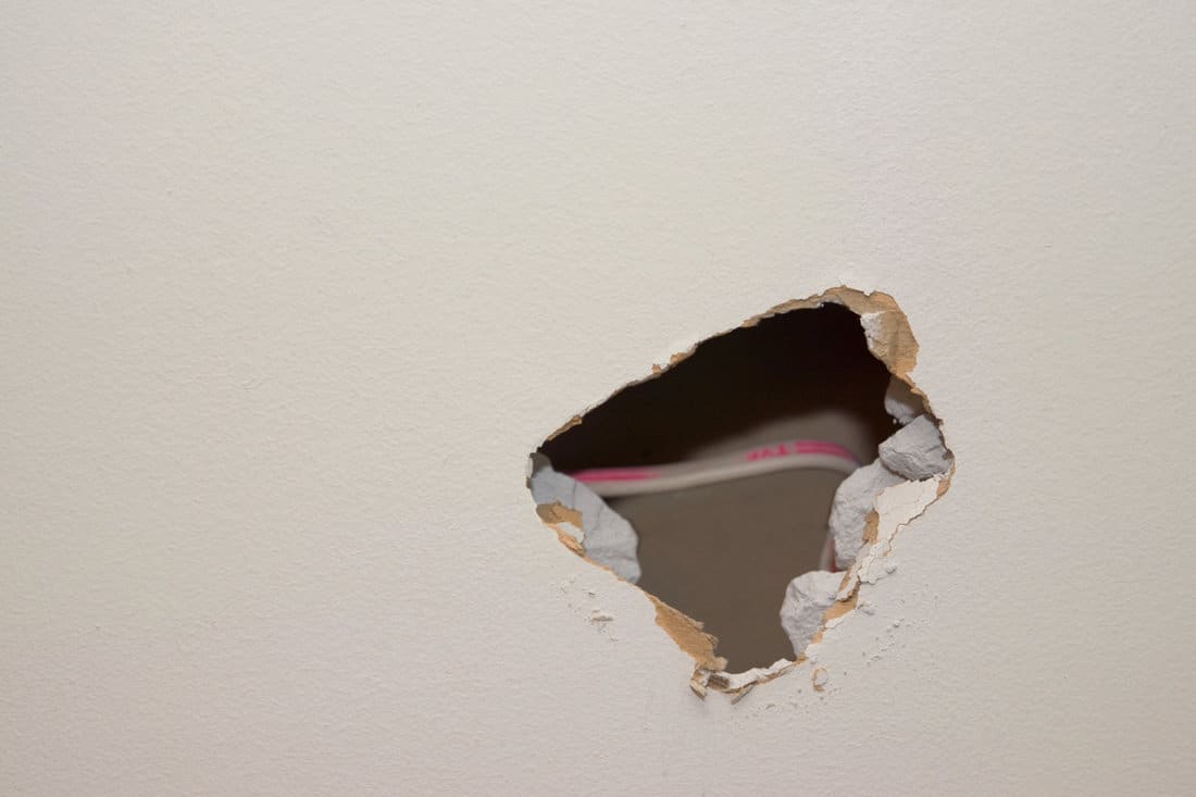 A huge hole on the drywall photographed in the living room