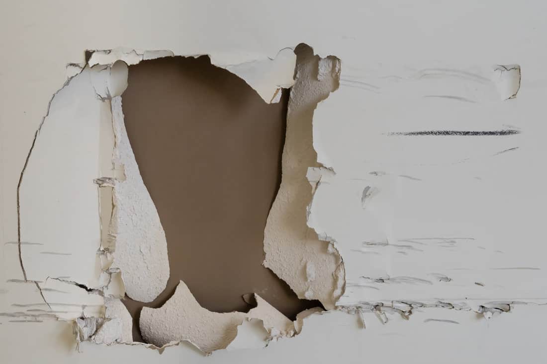 A huge hole on the drywall photographed up close