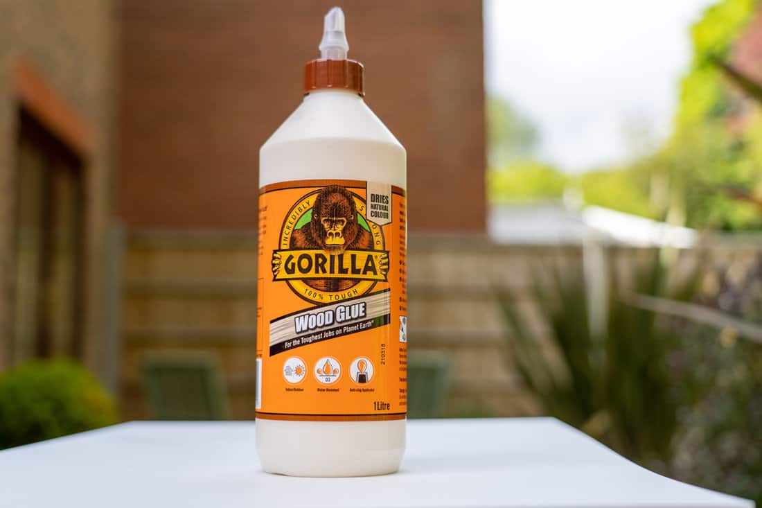 A litre squeeze bottle of gorilla wood glue on a white bench top outside distributed by The Gorilla Glue Company