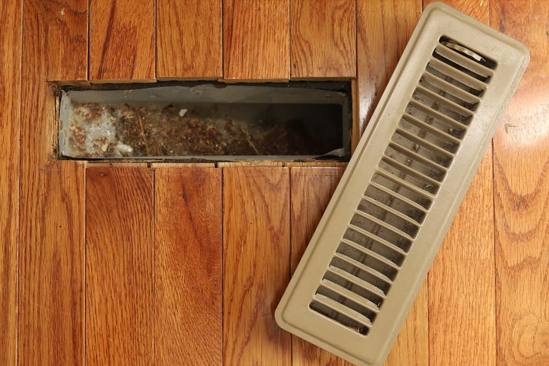 A opened heating/cooling vent register on the floor in a home home