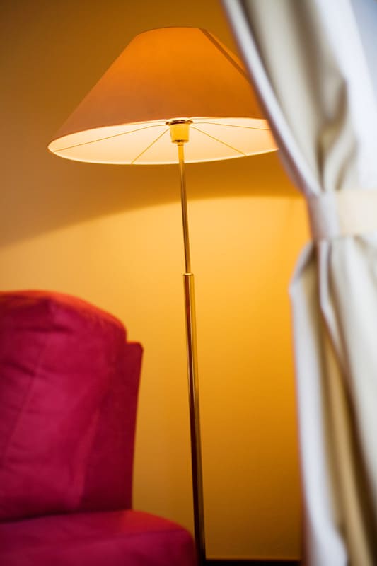 A tall floor lamp next to a red chair inside an orange living room