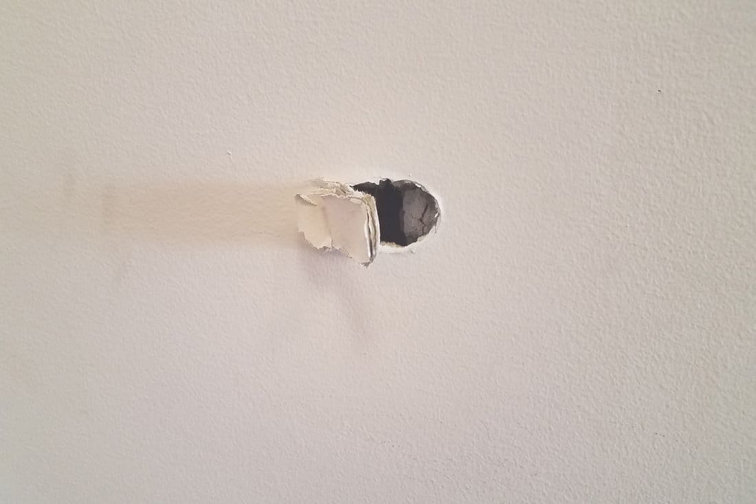 A white wall with a huge hole on it