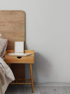 A wooden bedside table with a laptop on top and an empty picture frame, Can Nightstands Be Used As End Tables? [& How To]