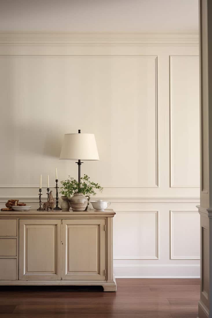 Wall painted in beige, adjacent to antique white trim and cabinets