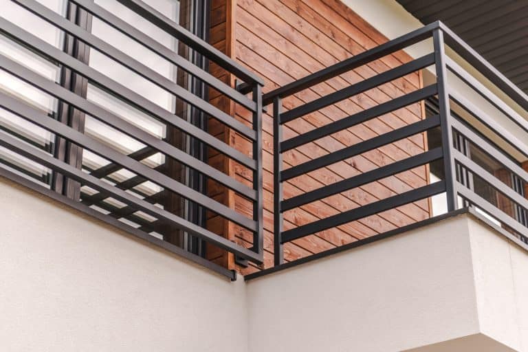 Black balcony railing. Wooden tile cladding. Two story modern mansion. Sliding door, How To Cover Balcony Railing For Privacy [Ideas To Inspire You]