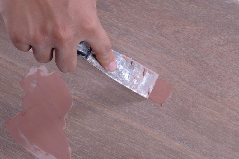 A carpenter using scraper and wood filler to fill the holes, Can You Drill Into Wood Filler? [Screw And Nails Issues]