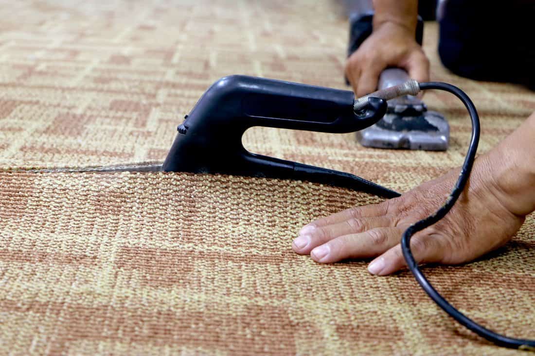 Carpet Binding - close-up of a craftman connecting the wall to wall carpet with heat bond iron.