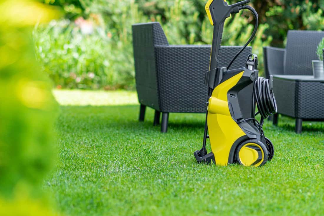 Cleaning garden furniture with high pressure washer. Outdoor, back yard.