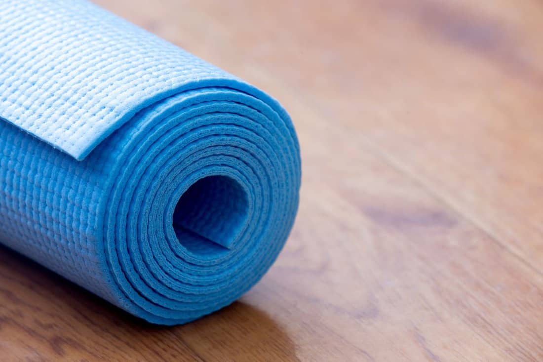 Close up of folded blue non-slip yoga, pilates mat on the floor. Healthy life, keep fit concepts, copy spase