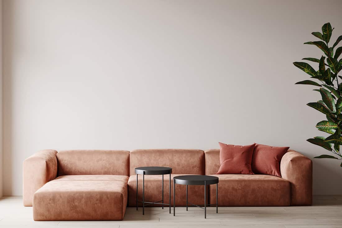 Living room with accent sectional sofa in coral or terracotta. Beige empty walls as background. Luxurious space for gallery or art. Colorful mockup design interior home.
