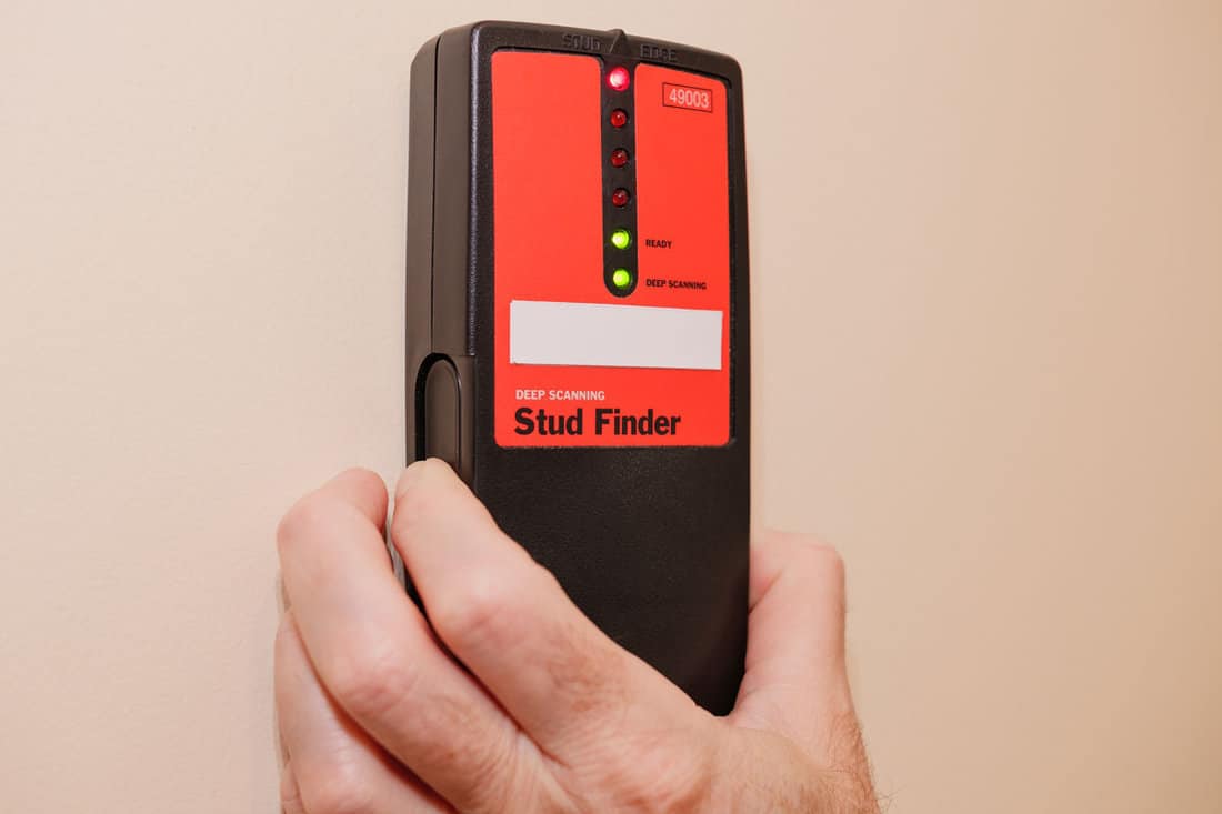 Male carpenter using electronic stud finder to locate interior wall stud