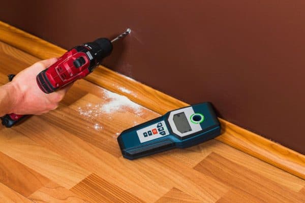 Man hand is scanning wall by cable detector to find a cable before drilling in. - How To Use A Craftsman Stud Finder [Step By Step Guide]