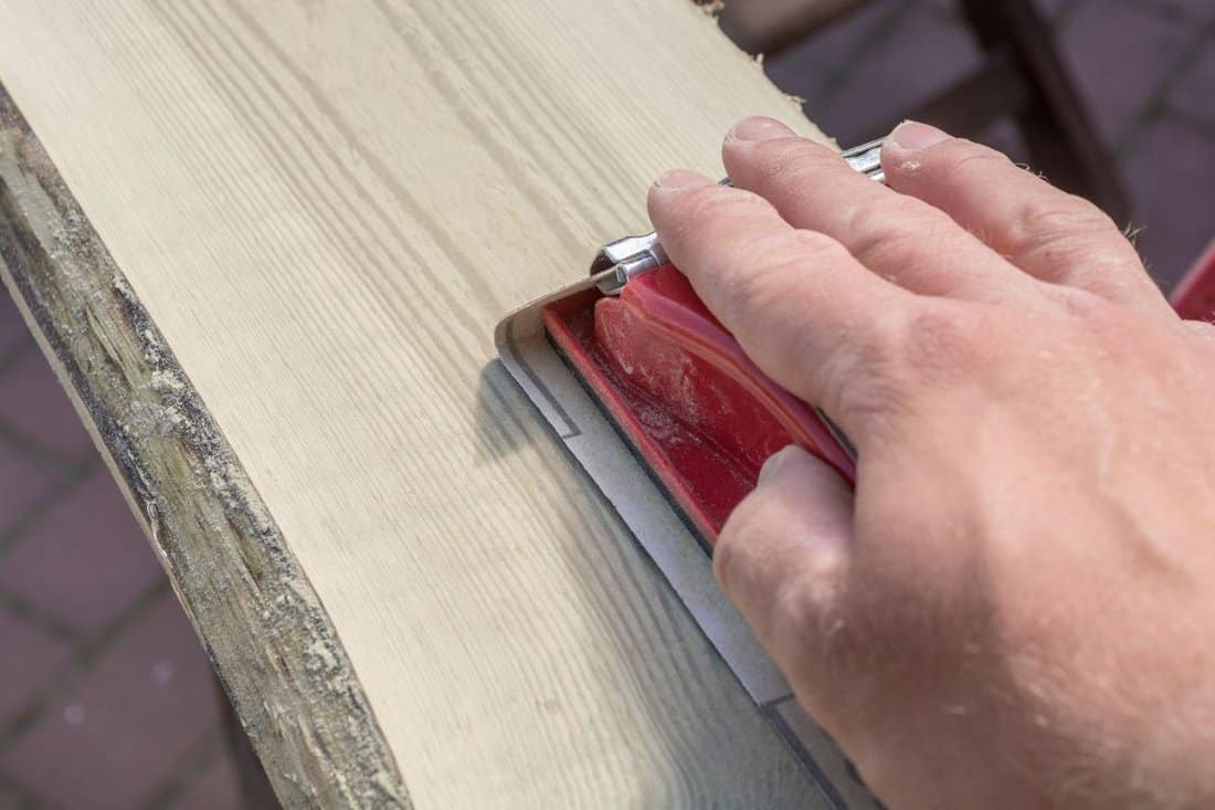 Preparation of an old wooden board by grinding with a hand sanding block stock photo