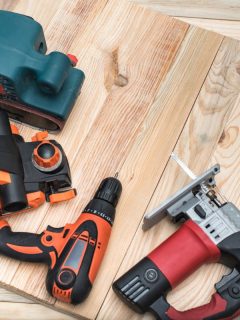 Set of handheld woodworking power tools for woodworking on light wooden background. Close up.