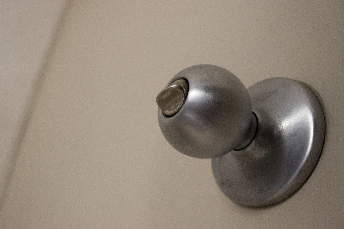 Silver iron doorknob in a closed wood door