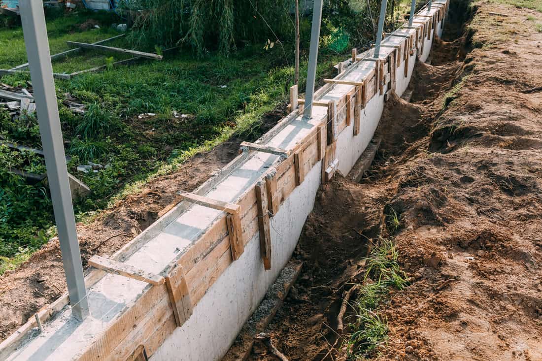 Timber formwork with metal reinforcement with pour concrete and creating a solid foundation for a building or fence. Construction process. Building the retaining wall. Side view. Nobody