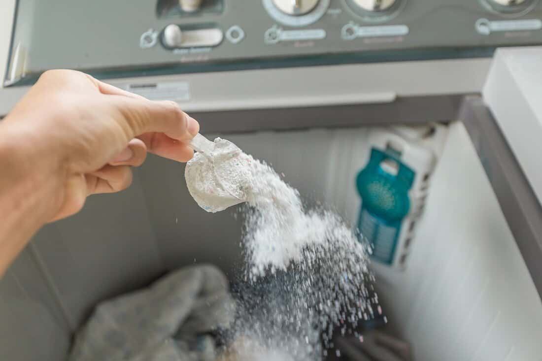 Too Much Detergent - man pouring washing powder into the washing machine tank