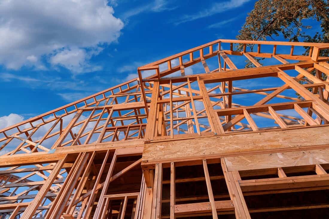 What is the purpose of roof framing - Home new wood frame stick built home under construction a blue sky