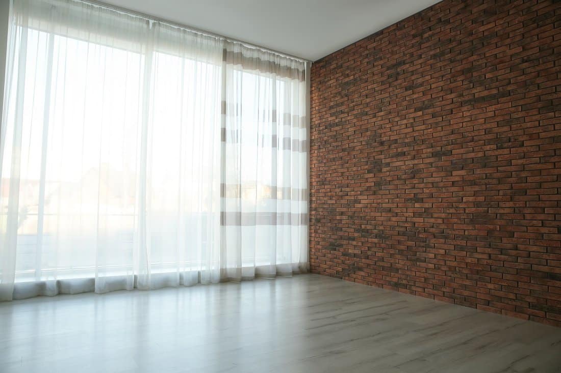 White- Empty room with red brick wall, large window and wooden floor