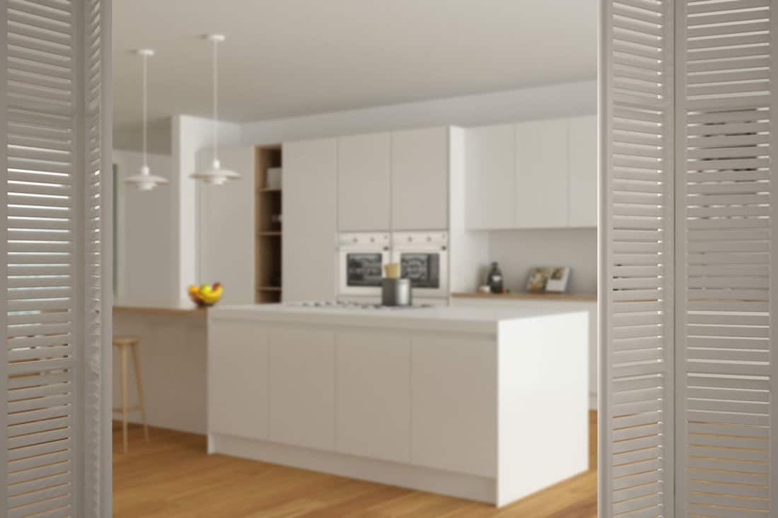 White folding door opening on modern minimalist white and wooden kitchen with island and big panoramic window,